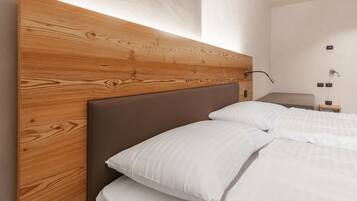 A modern bedroom with a wooden headboard, white bedding, and a bedside table with a lamp.