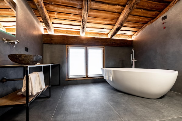 Une salle de bain moderne avec une baignoire sur pieds, un plafond en bois et une grande fenêtre.