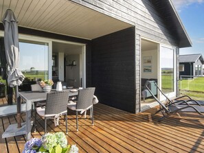 A covered outdoor area with a table and chairs, a grill, and a view of the surrounding landscape.