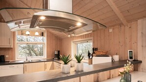 A modern kitchen with wooden walls, a black countertop, and a glass backsplash.