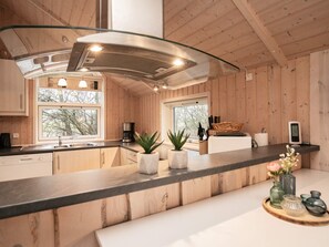 A modern kitchen with wooden walls, a black countertop, and a glass backsplash.