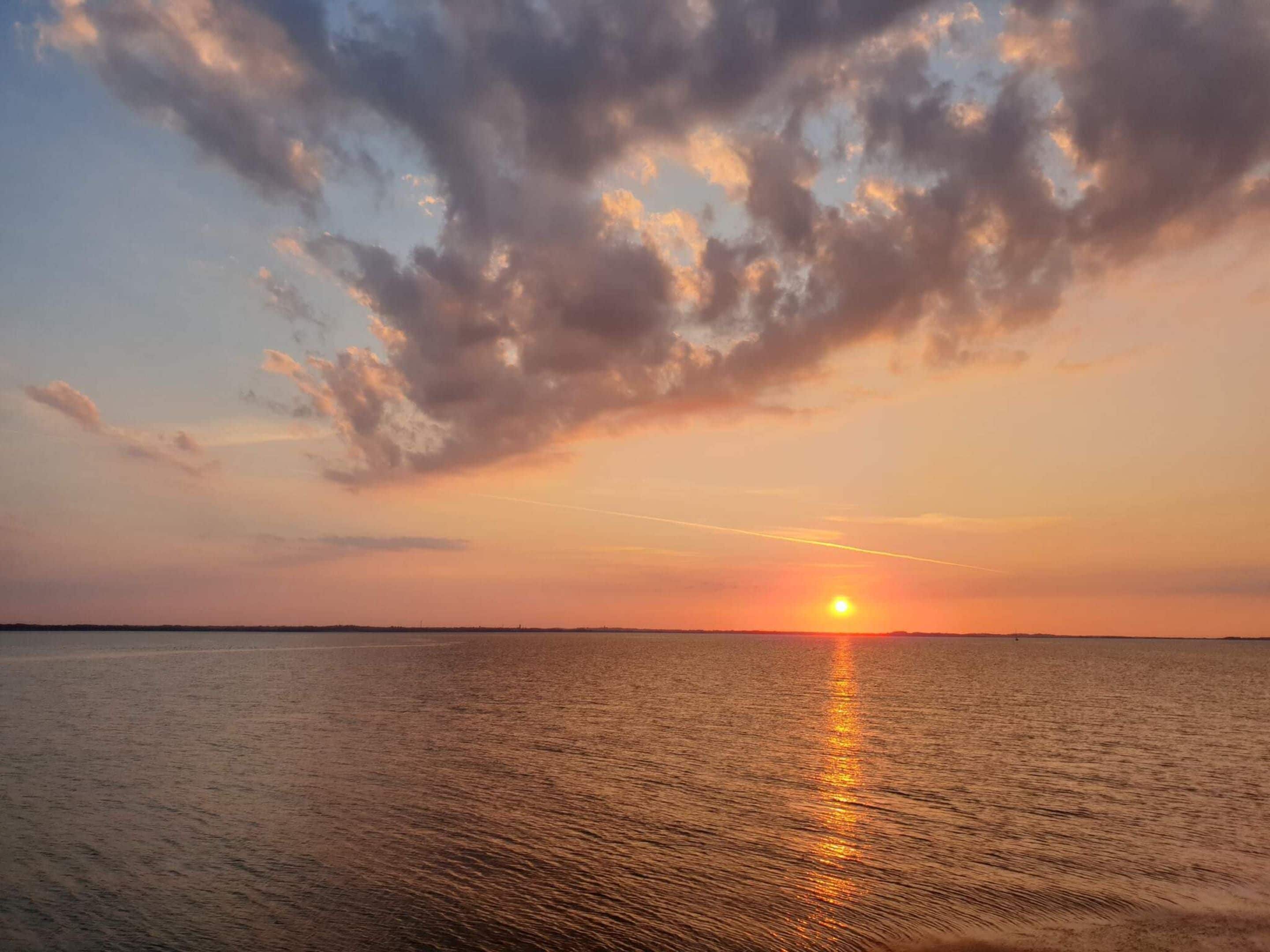 Ein Sonnenuntergang über ruhigem Wasser, der Horizont ist klar.