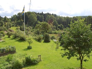 A grassy field with a flagpole and a flag, surrounded by trees and shrubs. - 5 Person Holiday Home in Floda (Floda)