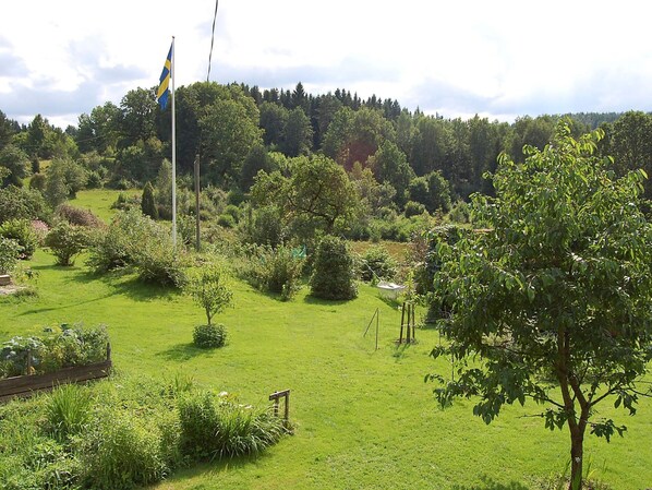 A grassy field with a flagpole and a flag, surrounded by trees and shrubs. - 5 Person Holiday Home in Floda (Floda)