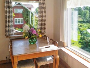 A dining table with a vase of flowers, a candle, and a window with curtains. - 5 Person Holiday Home in Floda (Floda)