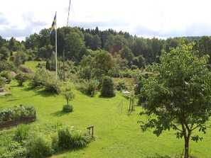 A grassy area with a flagpole, trees, and a wooden fence.