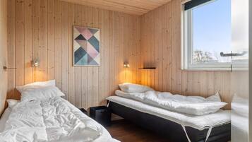 A room with two beds, wooden walls, a geometric artwork, and a window.