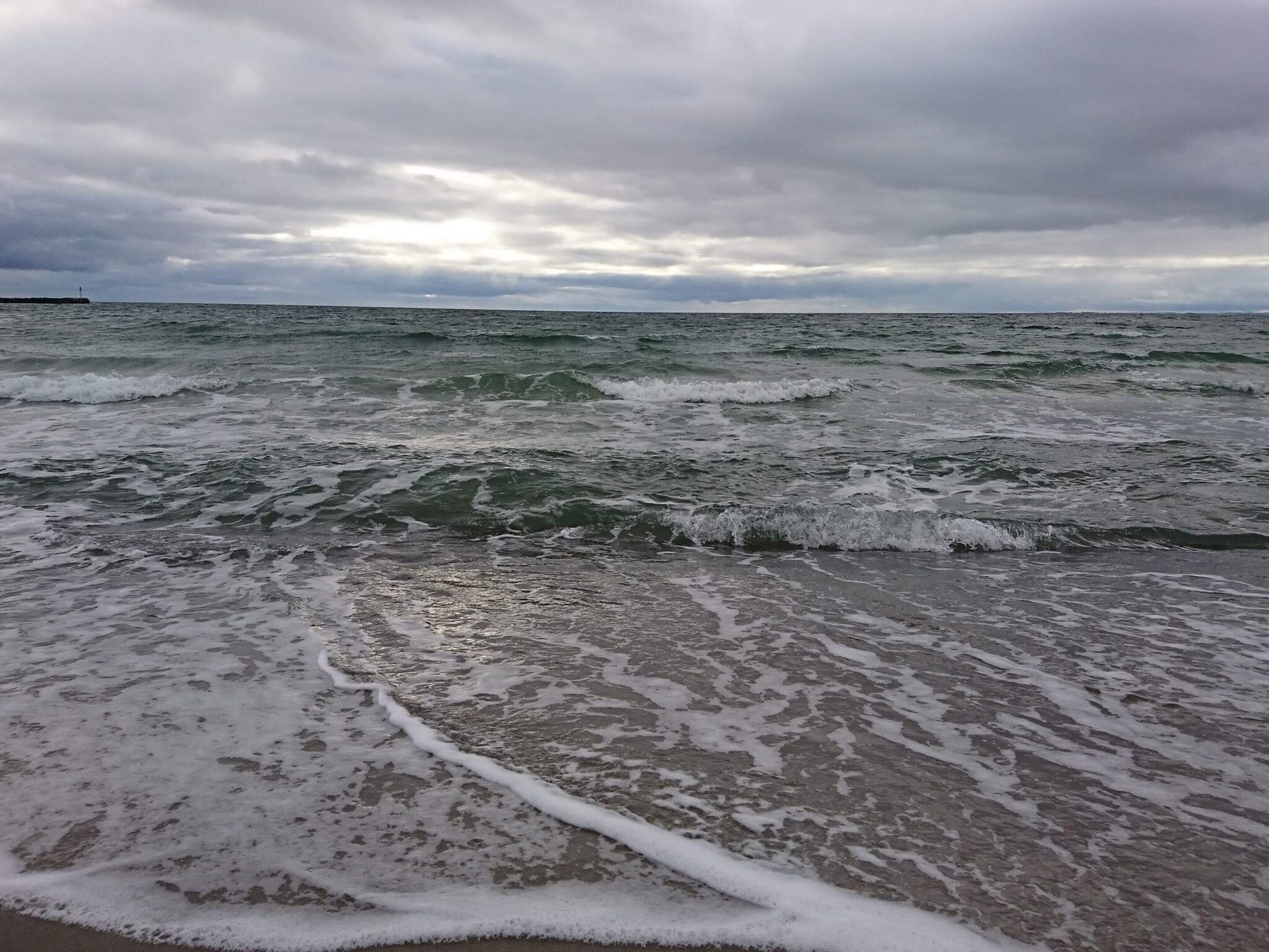 Una playa con olas y cielo nublado.