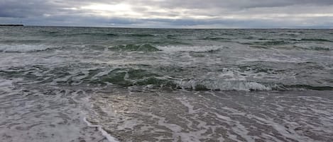 Une plage avec des vagues et un ciel nuageux.