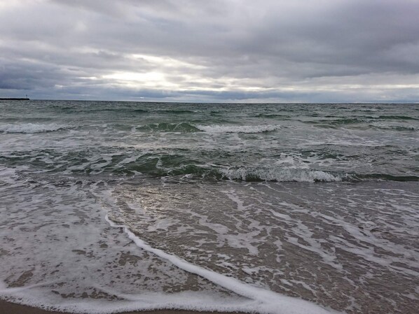 Una playa con olas y cielo nublado.