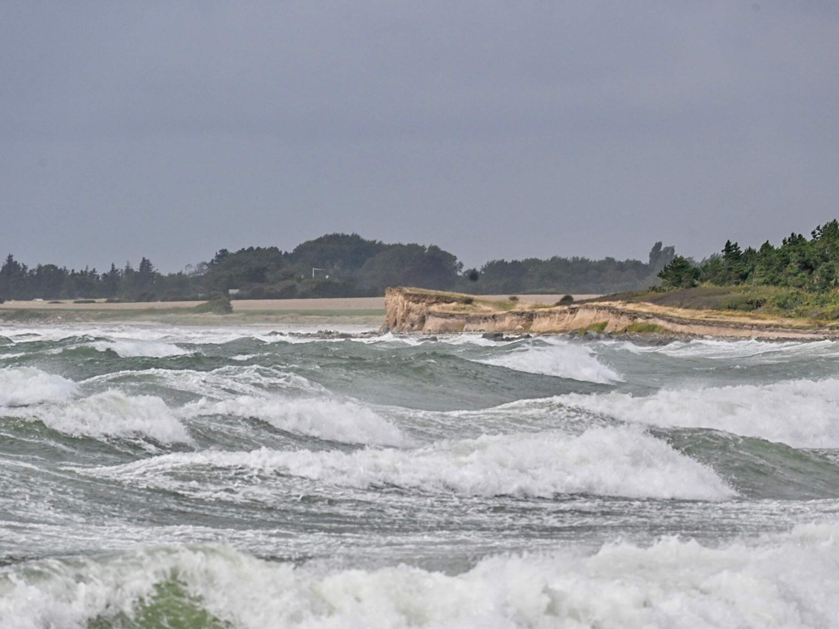 A coastal scene with waves crashing against a rocky outcrop.