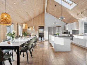 Una cocina moderna con una isla central, suelo de madera e iluminación colgante.