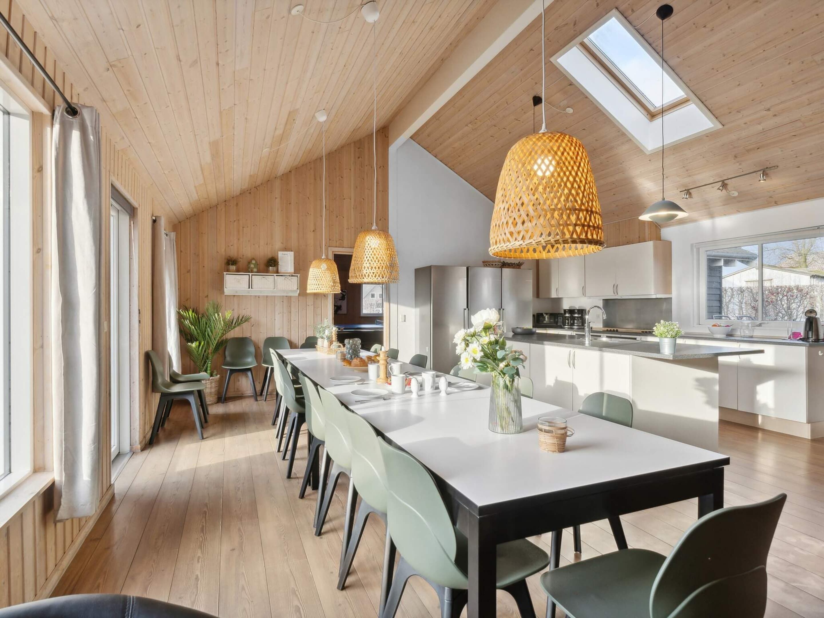 A modern kitchen with a central island, pendant lighting, and a view of the outdoors.