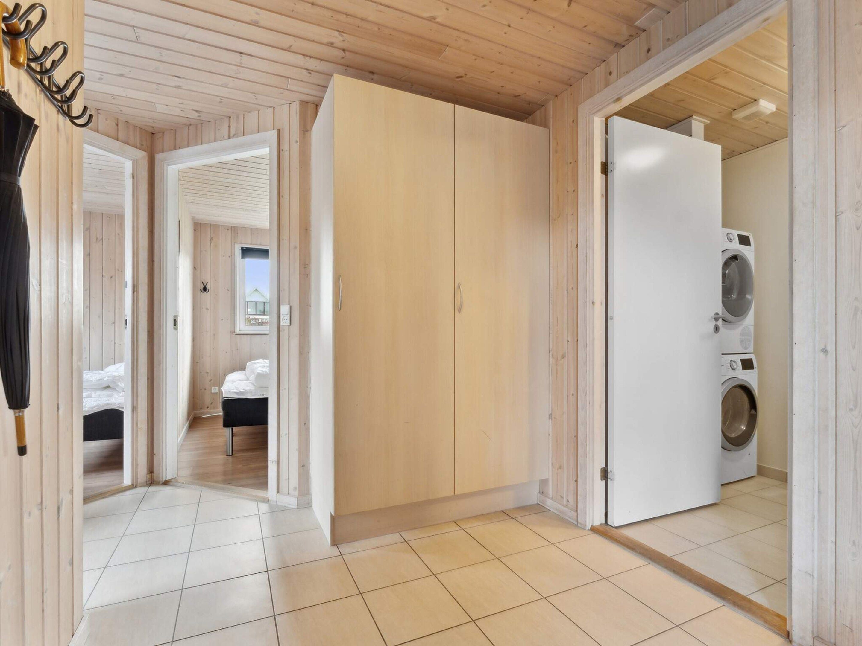A wooden interior with a bed, a wardrobe, and a washing machine.