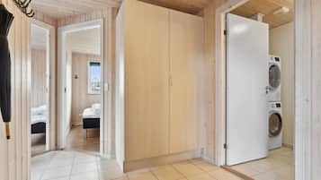 A wooden interior with a bed, a wardrobe, and a washing machine.