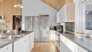 A modern kitchen with stainless steel appliances, white cabinetry, and a wooden ceiling. - 4 Star Holiday Home in Bagenkop (Sydlangeland)