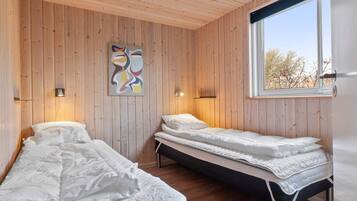 A room with two beds, wooden walls, a window, and a painting.