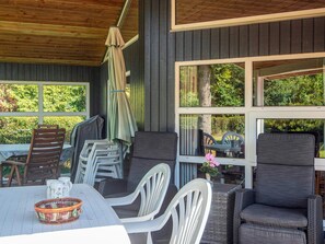 An outdoor seating area with a table and chairs, a wicker chair, and a covered umbrella.