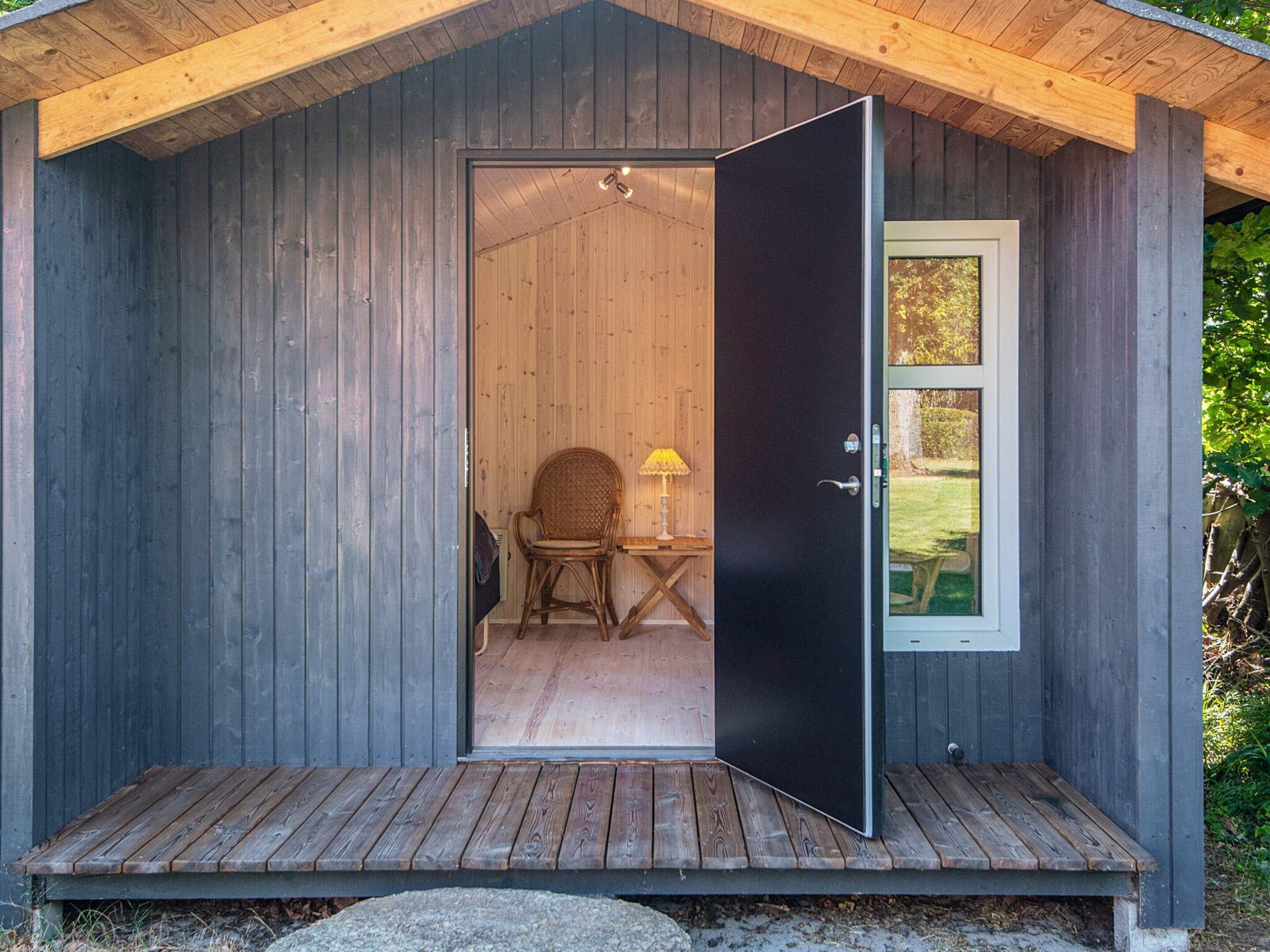 A wooden cabin with a dark door, a small table, and a chair inside.