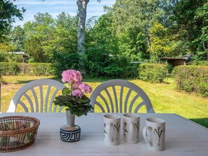 Ein Tisch mit einer Blumenvase, einem gewebten Korb und drei Tassen mit Blumenmotiven.