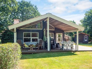 A two-story house with a covered porch, a deck, and a small shed in the background. - 4 Star Holiday Home in Glesborg (Glesborg)