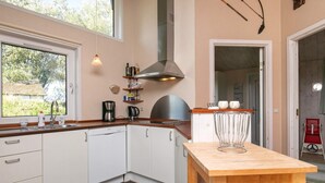 A kitchen with white cabinets, a wooden countertop, a coffee maker, and a kettle.