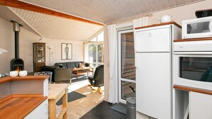 A compact kitchen with a built-in oven, a microwave, and a stove. There is a dining area with a table and chairs, and a window providing natural light.