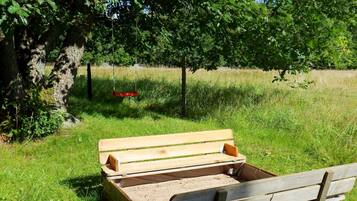 Un banco de madera en un campo cubierto de hierba, con árboles al fondo.