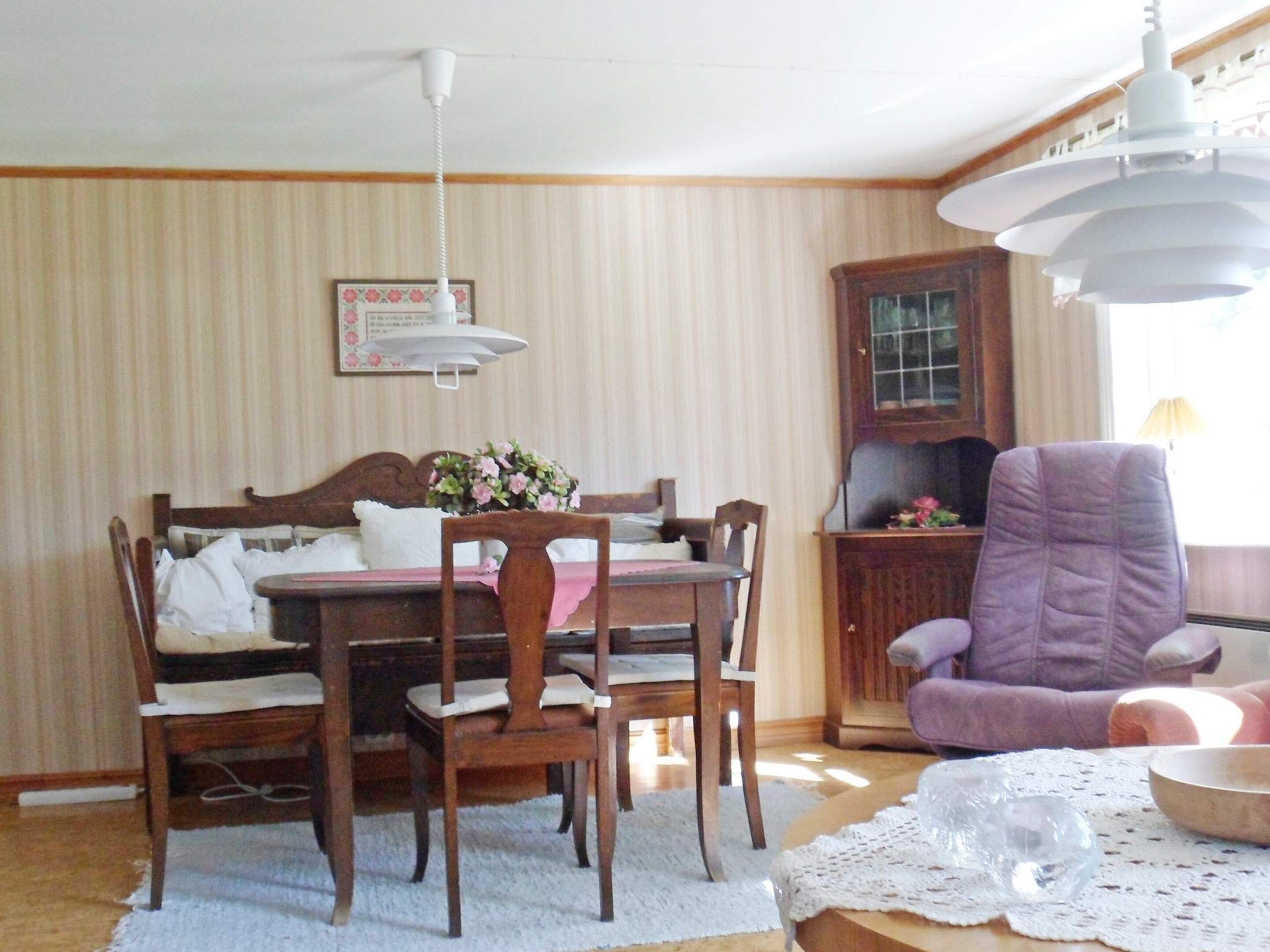 A dining area with a wooden table and chairs, a purple armchair, and a ceiling fan.