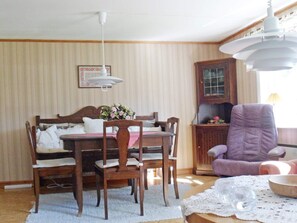 Un comedor con una mesa y sillas de madera, un sillón púrpura y un ventilador de techo.