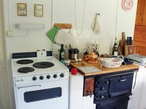 Una cocina con estufa blanca, horno negro y encimera de madera, además de diversos utensilios de cocina.