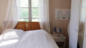 A bedroom with a bed, a nightstand, a lamp, a mirror, and a wardrobe.
