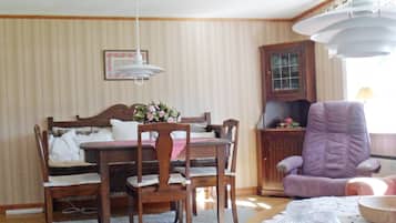 A dining area with a wooden table and chairs, a purple armchair, and a ceiling fan.