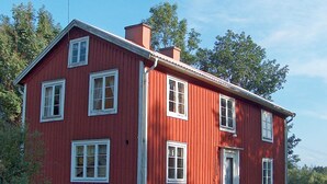 Una casa de madera roja con varias ventanas y una chimenea.