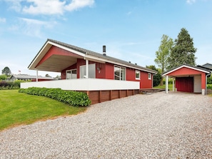 En röd byggnad med en inglasad veranda och ett separat garage.