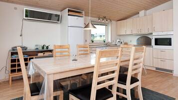 A modern kitchen with wooden cabinets, a dining table with chairs, and a built-in oven.