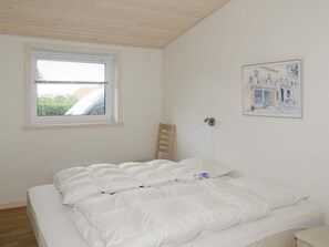 A bedroom with a bed, a window, a chair, and a wall-mounted light fixture. - 4 Star Holiday Home in Hejls (Hejls)