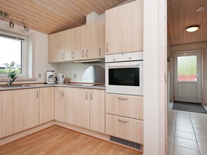 Una cocina moderna con armarios de madera, horno empotrado y ventana con vistas al exterior.