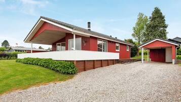 A red building with a covered porch and a separate garage.
