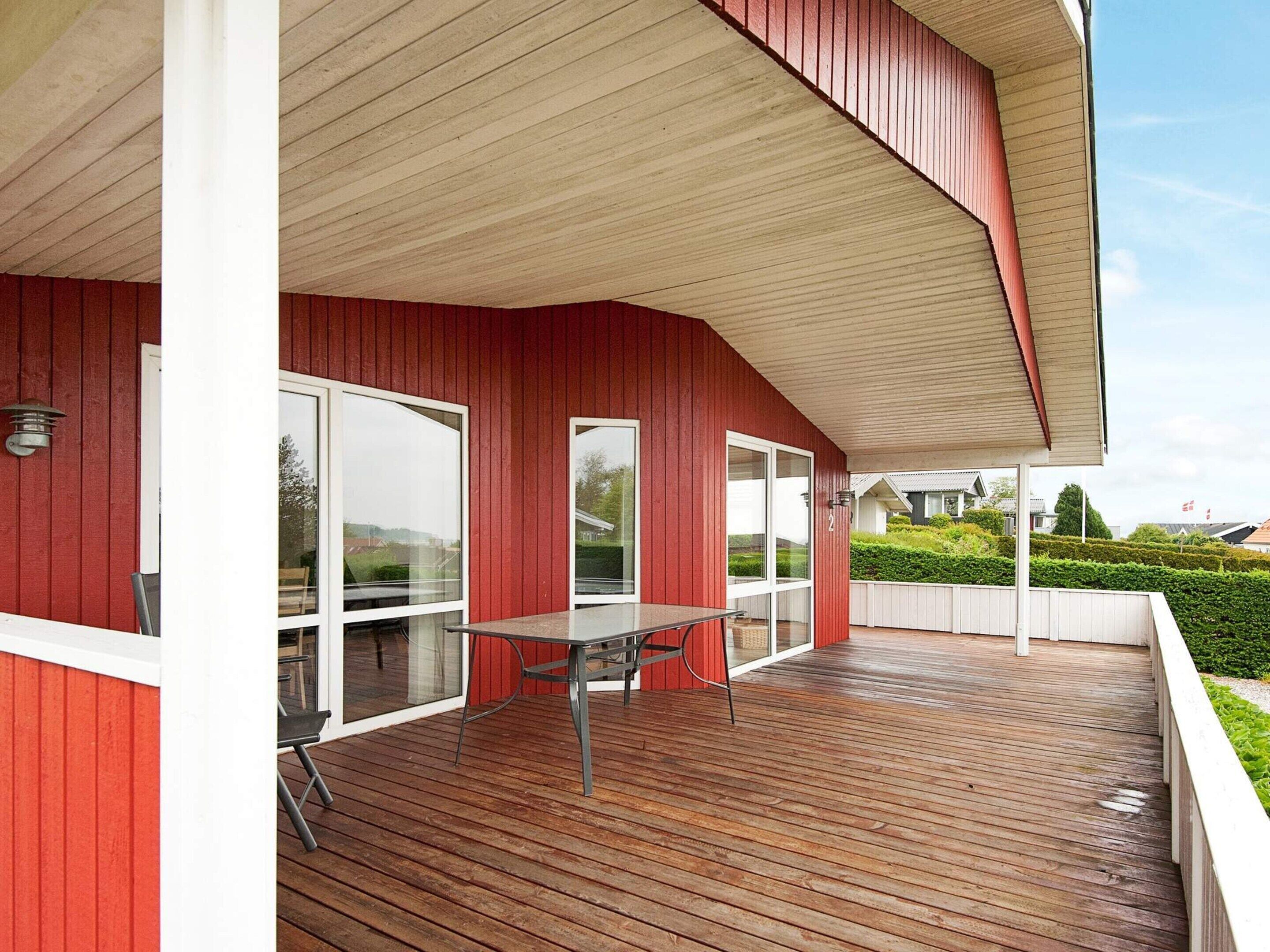 A covered outdoor area with a wooden deck, a table, and chairs.