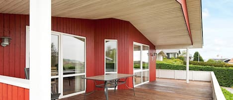 Un espacio al aire libre cubierto con una terraza de madera, una mesa y sillas.