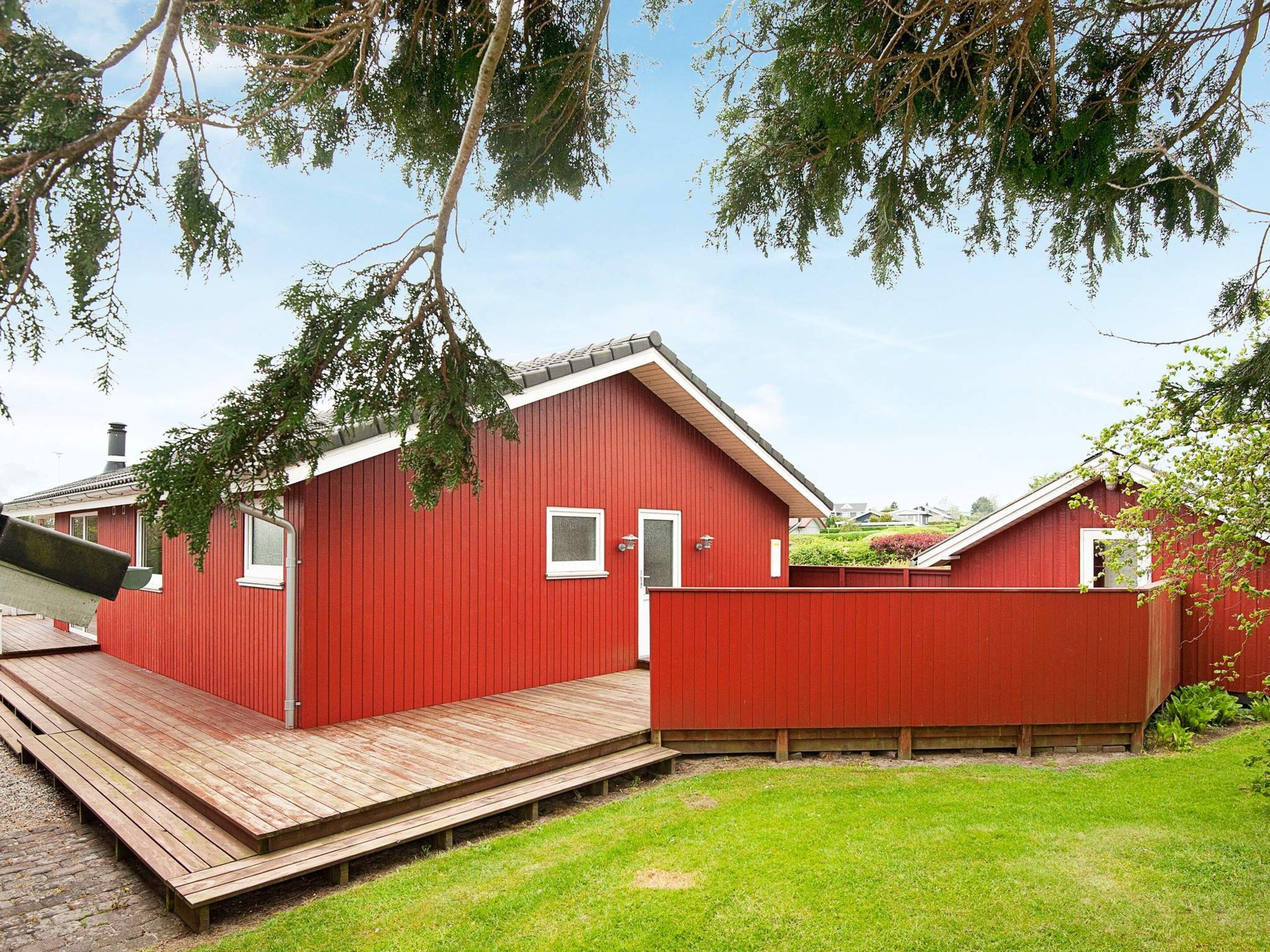 A red wooden building with a small window, a door, and a wooden deck.