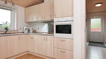 A modern kitchen with wooden cabinets, a built-in oven, and a window with a view of the outside.