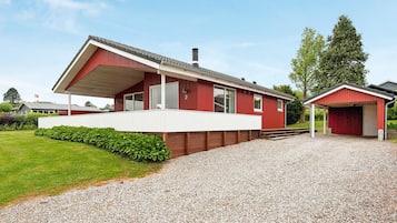 A red building with a covered porch and a gravel driveway.