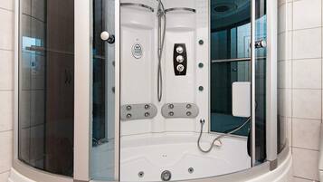 A modern, enclosed shower area with a control panel, a handheld showerhead, and a built-in seat.