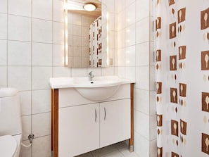 Un baño con lavamanos blanco, espejo y retrete.