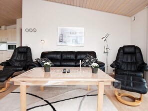 A modern living room with a black leather sofa, two black leather chairs, a wooden coffee table, and a black and white patterned pillow. - 4 Star Holiday Home in Hejls (Hejls)