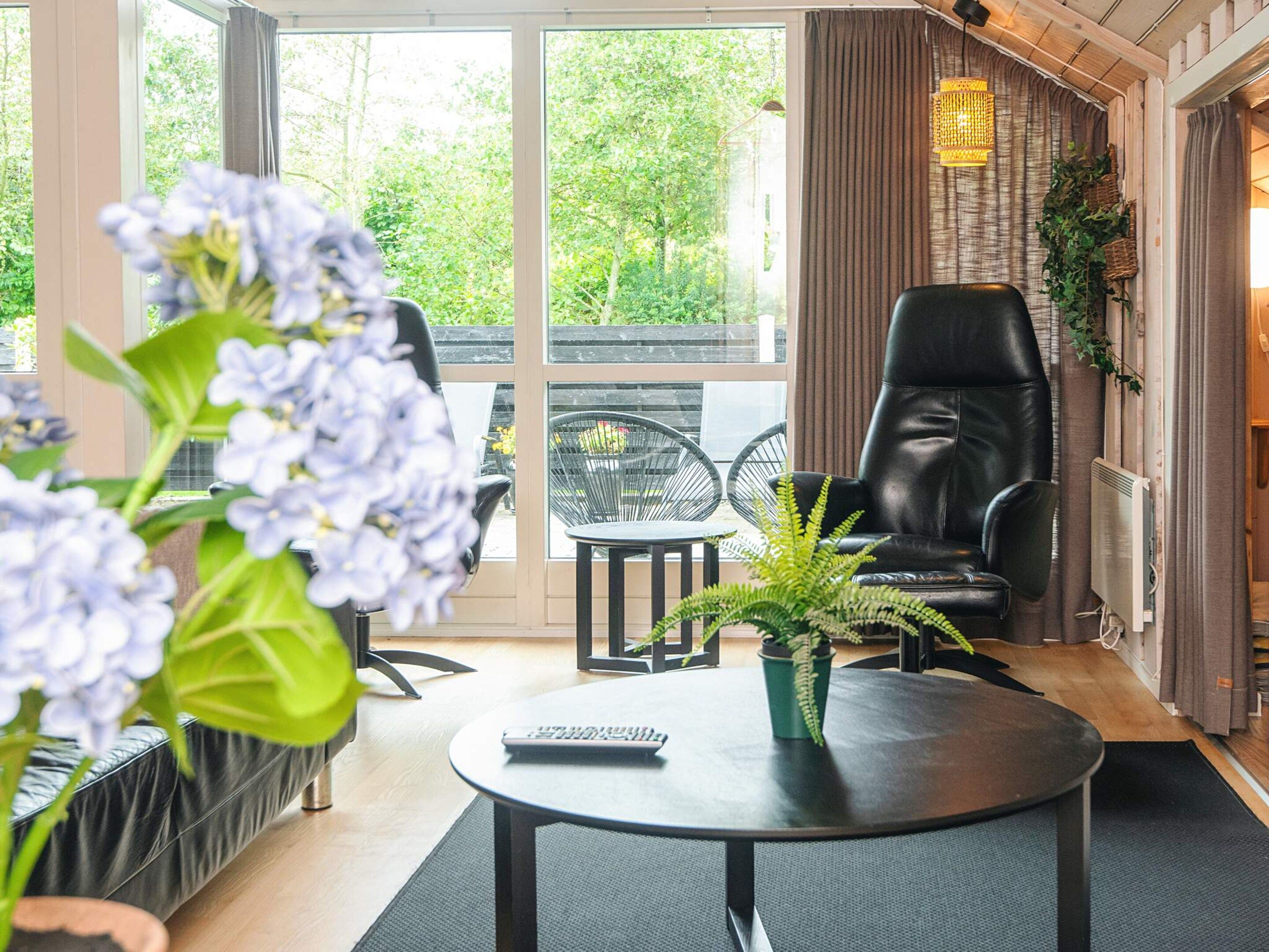 A modern indoor seating area with a leather chair, a round table, and a potted plant.