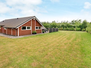 A single-story house with a sloped roof, a paved driveway, and a well-maintained lawn.