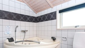 Ein Badezimmer mit einer freistehenden Badewanne, einer Toilette und einem Fenster.